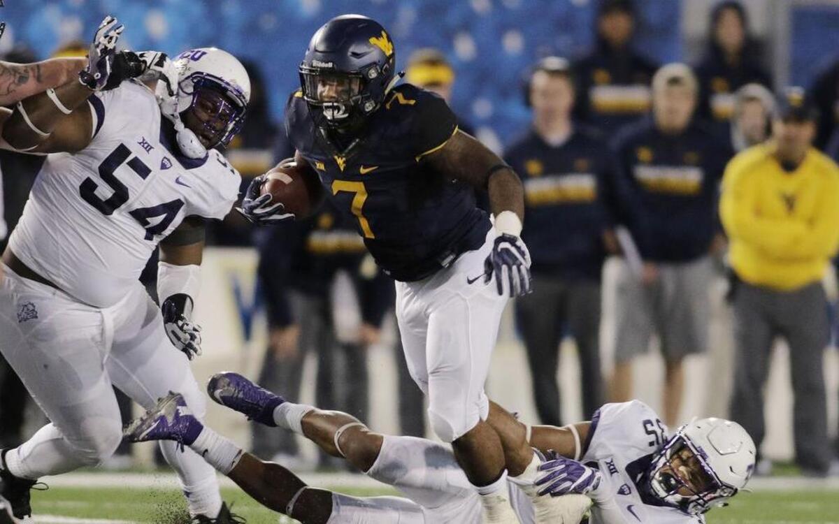 TCU defensive tackle Joseph Broadnax (left) and linebacker Sammy Douglas try to make a stop against West Virginia running back Rushel Shell during second-half action Saturday in Morgantown.