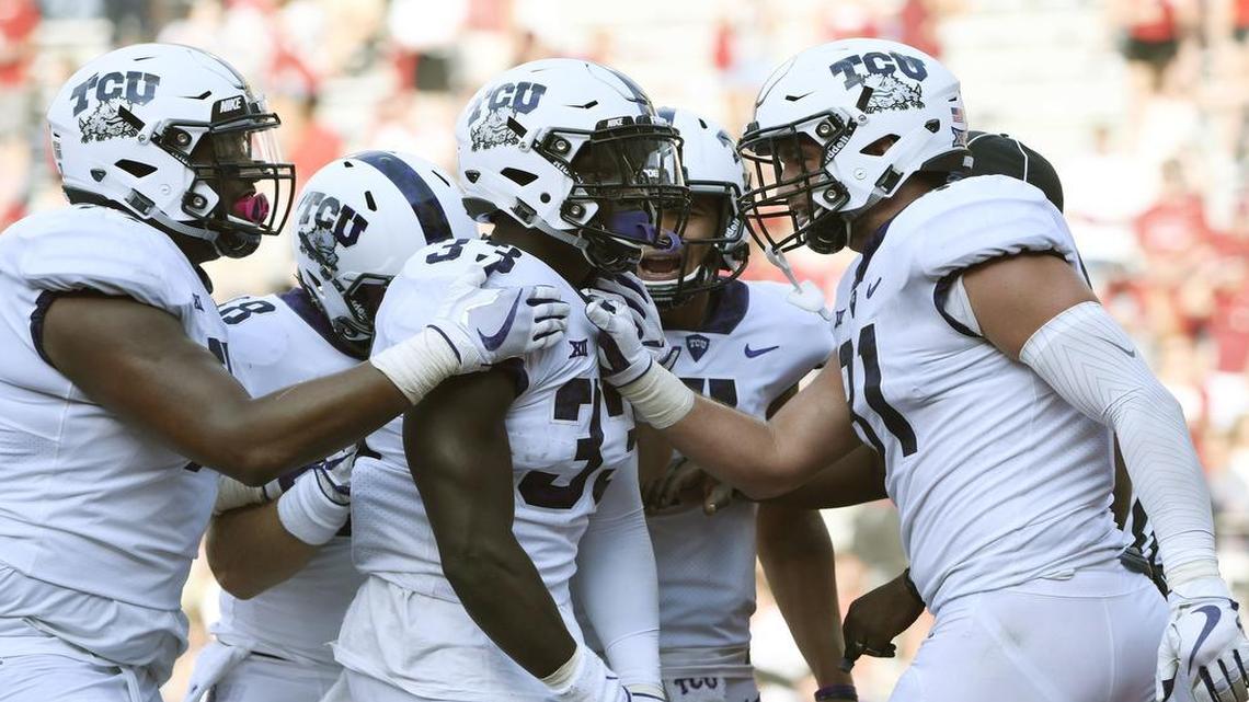 TCU running back Sewo Olonilua (center) gets congratulations from teammates Lucas Niang (left) and Cole Hunt after scoring the final touchdown in the Horned Frogs’ 28-7 victory against Arkansas at Reynolds Razorback Stadium.