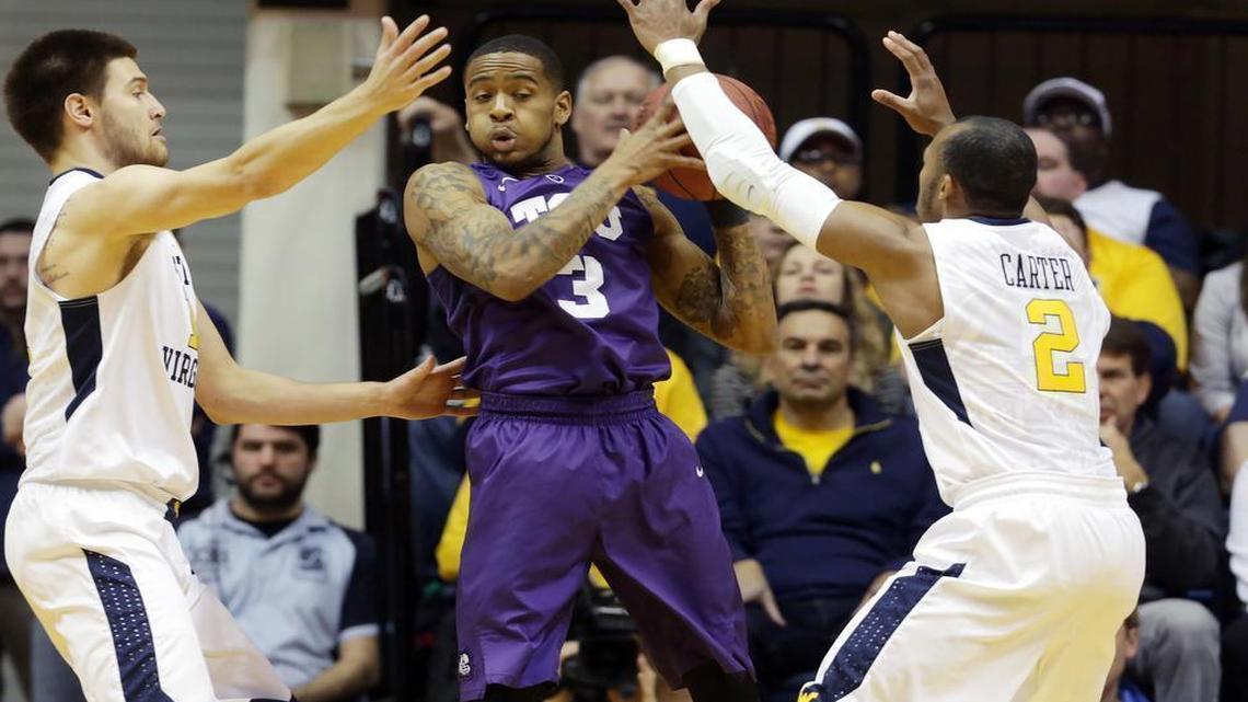 West Virginia forward Nathan Adrian, left, and guard Jevon Carter (2) trap TCU guard Malique Trent (3) during the first half Saturday, in Morgantown, W.Va.
