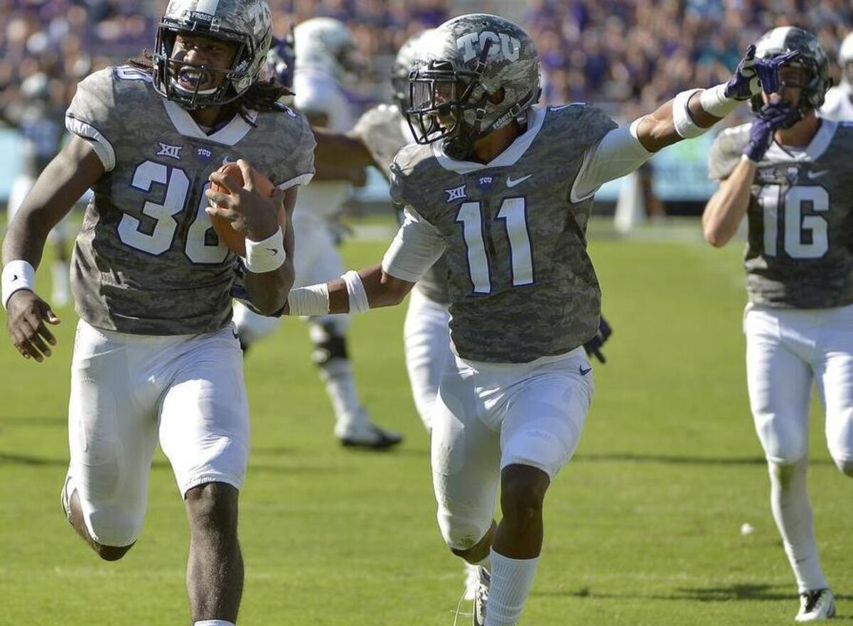 
TCU safety Denzel Johnson returns an interception 50 yards for a touchdown Saturday, with an escort from Ranthony Texada.
