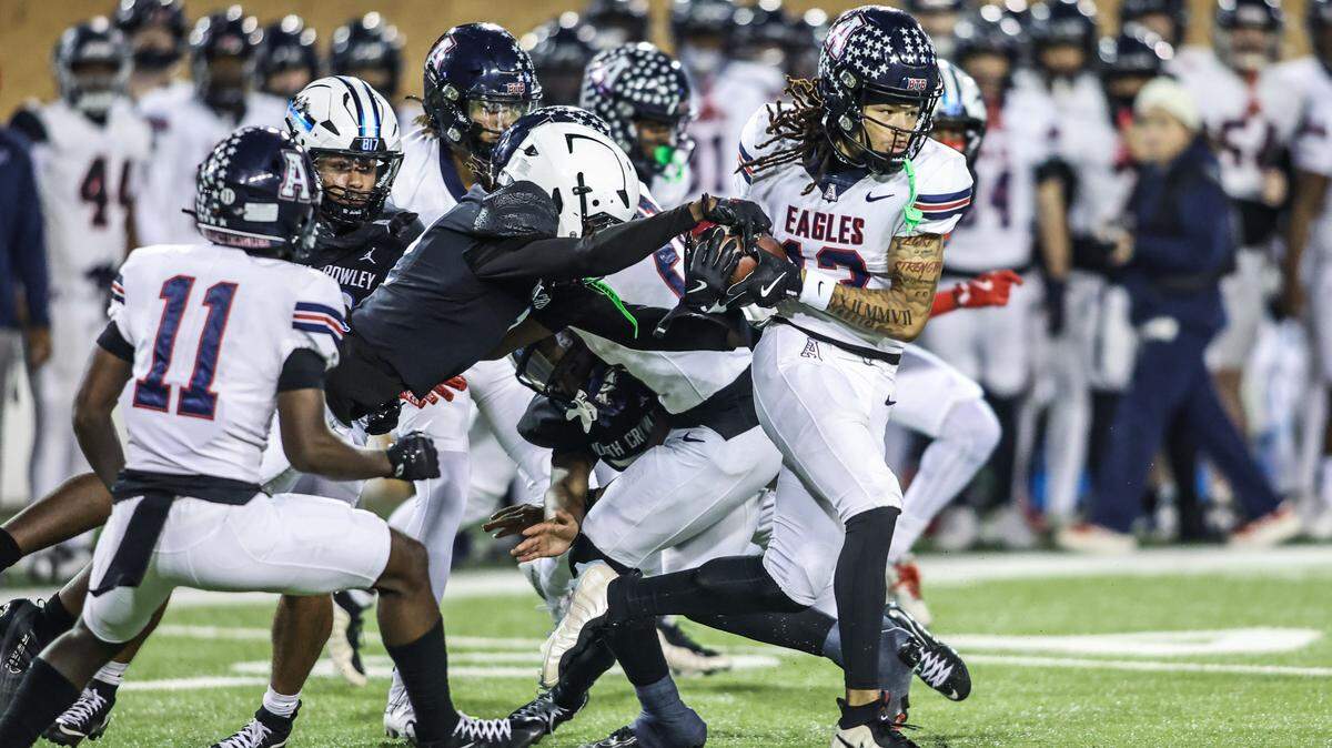 A North Crowley player tries to pull the ball away from Allen’s LeBron Bauer (13) during the Class 6A Division I regional final Friday at DATCU Stadium in Denton.
