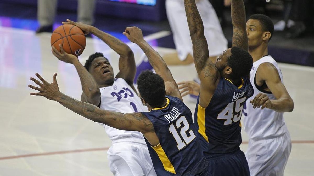 TCU guard Chauncey Collins forces up a shot over West Virginia guard Tarik Phillip and forward Elijah Macon.