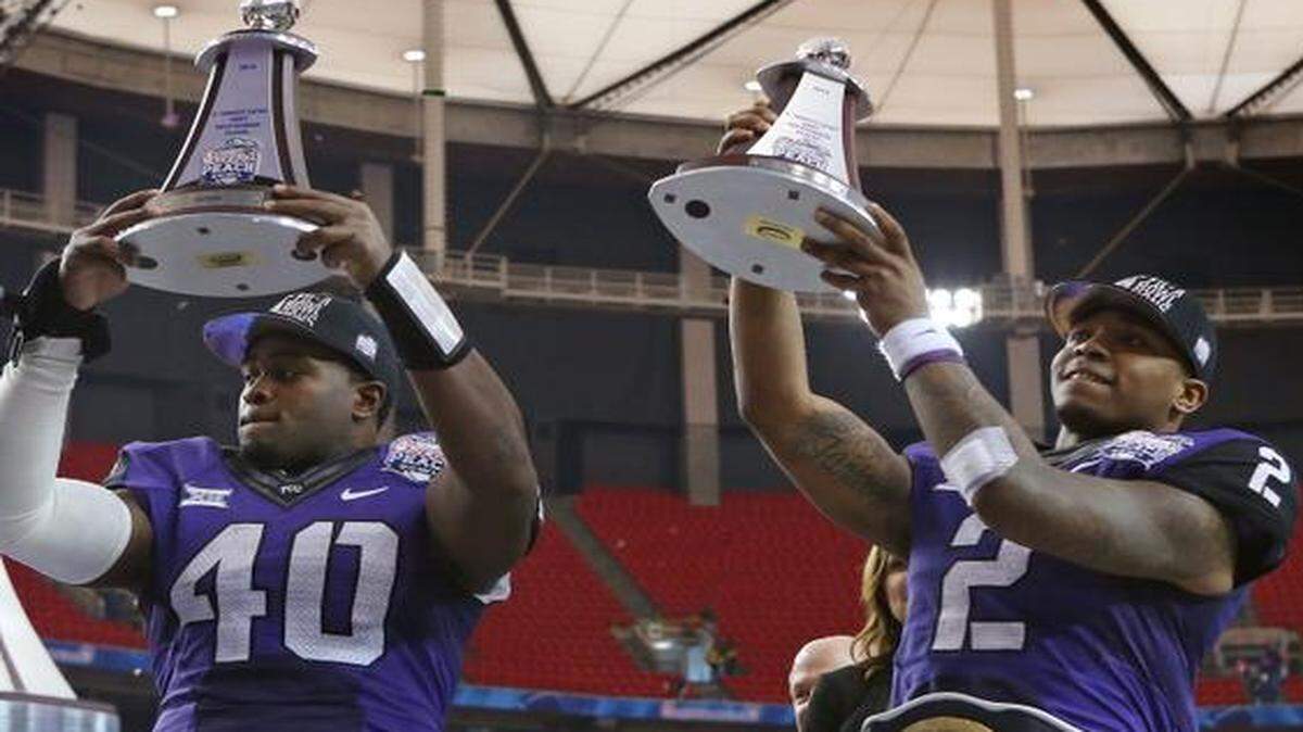 
Peach Bowl defensive and offensive MVP winners, TCU defensive end James McFarland, left, and quarterback Trevone Boykin, raiseg their trophies after the Horned Frogs beat Mississippi 42-3 on Wednesday to win the 2014 Peach Bowl in Atlanta. 
