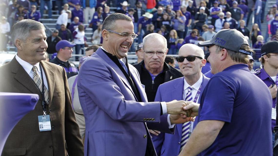 TCU athletic director Chris Del Conte (center) congratulates coach Gary Patterson during an on-field ceremony to present a Big 12 championship trophy following a 55-3 victory against Iowa State on Dec. 6, 2014. Big 12 commissioner Bob Bowlsby (left) and TCU chancellor Dr. Victor Boschini (second from right) look on.
