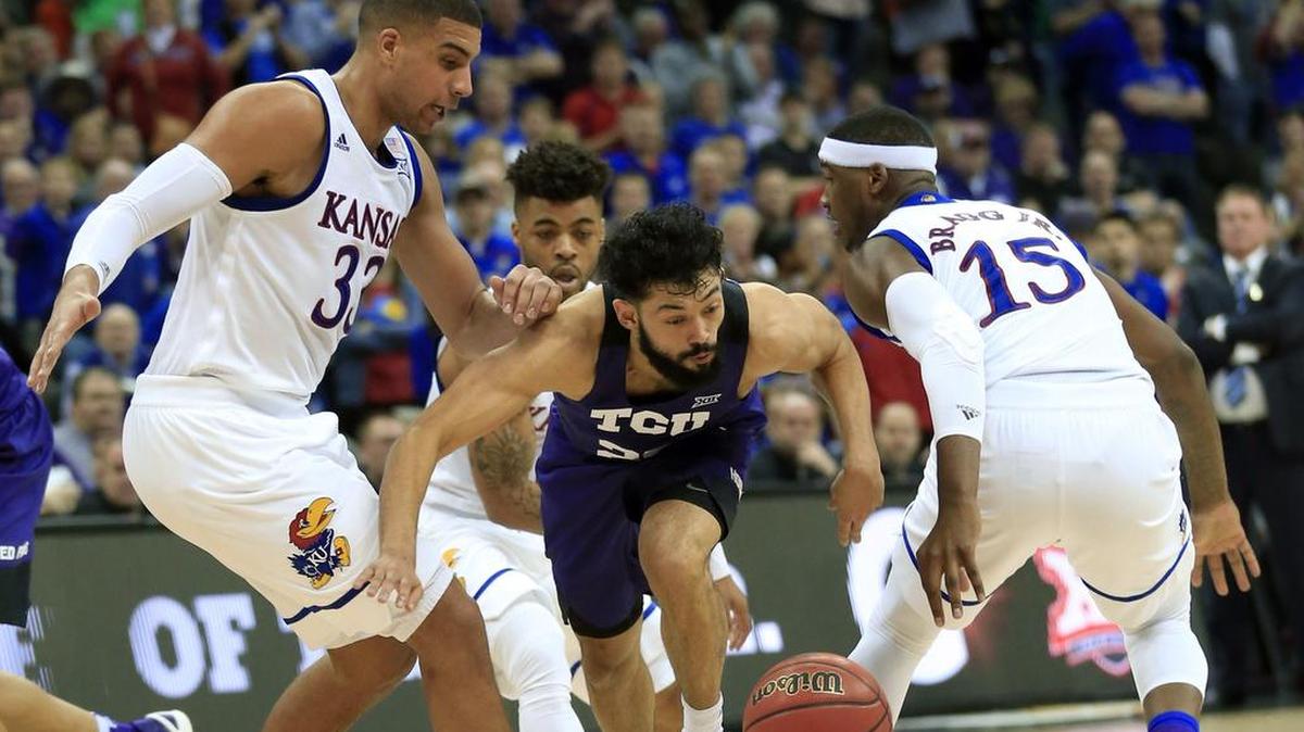 TCU guard Alex Robinson dribbles between Kansas defenders Landen Lucas (left) and Carlton Bragg Jr. during the second half of a quarterfinal game at the Big 12 tournament on March 9. TCU won the game to uspet the top-ranked Jayhawks and win two games in the league postseason event for the first time.
