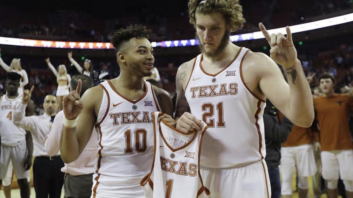 Texas guard Eric Davis Jr. (10) and forward Dylan Osetkowski (21) hold the jersey of teammate Andrew Jones (1) during the school song following an NCAA college basketball game against TCU, Wednesday, Jan. 10, 2018, in Austin. The team debuted the “AJ1” logo on their jerseys to honor guard Jones, who has been diagnosed with leukemia. Texas won in double overtime, 99-98.