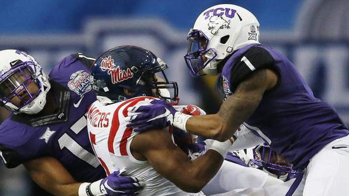 In this file photo, TCU safety Sam Carter, left, teams up with Chris Hackett to corral Mississippi running back I’Tavius Mathers during the Peach Bowl on Dec. 31, 2014.. Carter is currently an assistant coach for Arkansas, which takes on TCU on Thursday in the Texas Bowl in Houston.