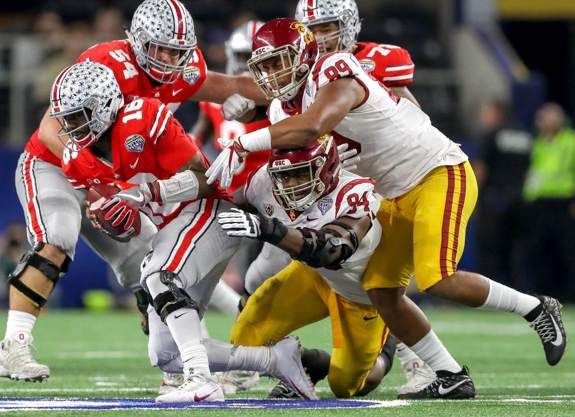 Ohio State quarterback J.T. Barrett (16) is pressured by USC defensive lineman Rasheem Green (94) and lineman Christian Rector (89) during the first half.