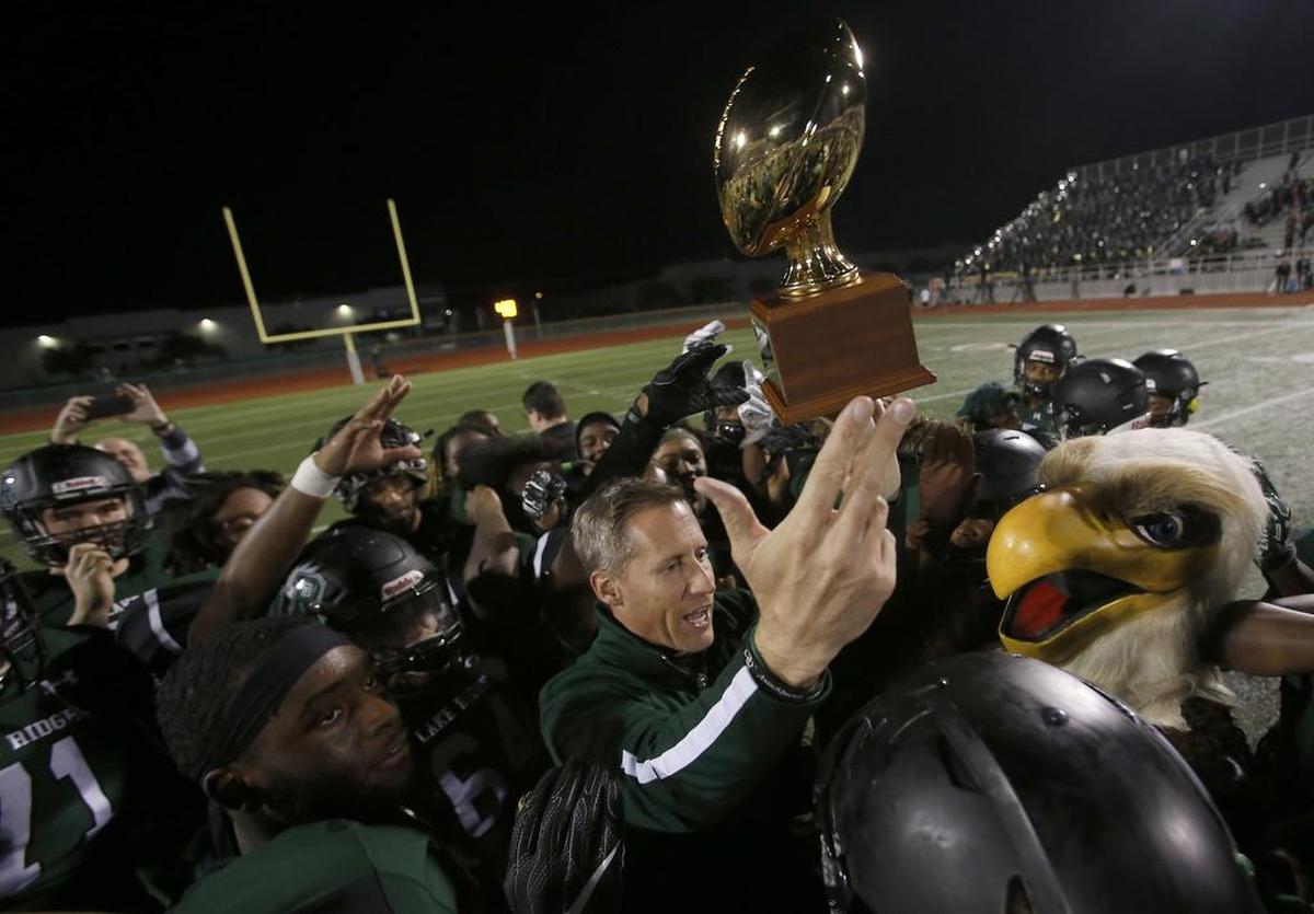 Mansfield Lake Ridge Eagles head coach Kirk Thor lifts the Class 5A Division I regional round trophy on Friday Dec. 1. Lake Ridge is moving up to Class 6A next school year.