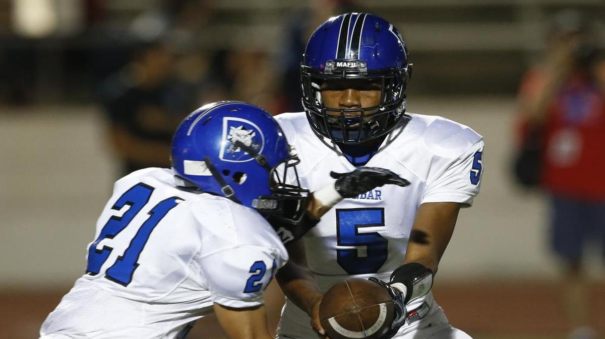 Dunbar quarterback Nakkia Cox hands off to running back Timothy Crossley during a game this season. The Wildcats, whose enrollment of 872 is well below the Class 5A range of 1,060-2,099, will again opt up for next year’s realignment for athletics.