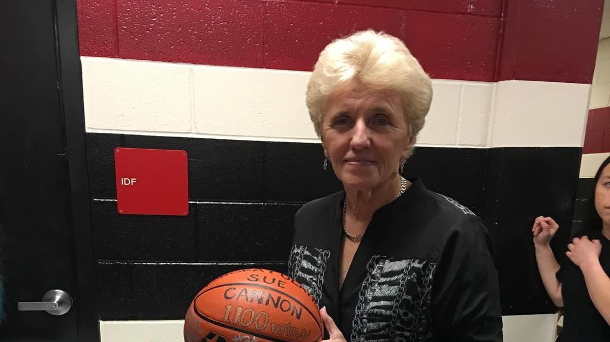 Trinity girls basketball coach Sue Cannon shows off the game ball from her 1,100th career win.