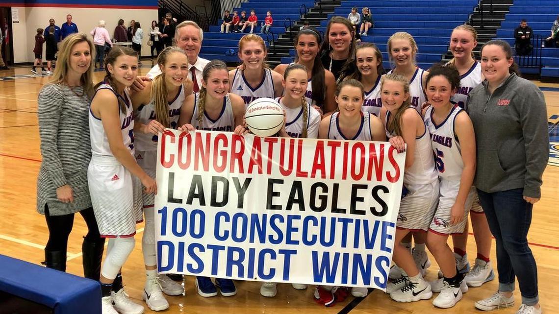 Lake Country Christian girls basketball coach Eric Boettcher (back row, second from left) and his team commemorates 100 consecutive district wins on Tuesday.