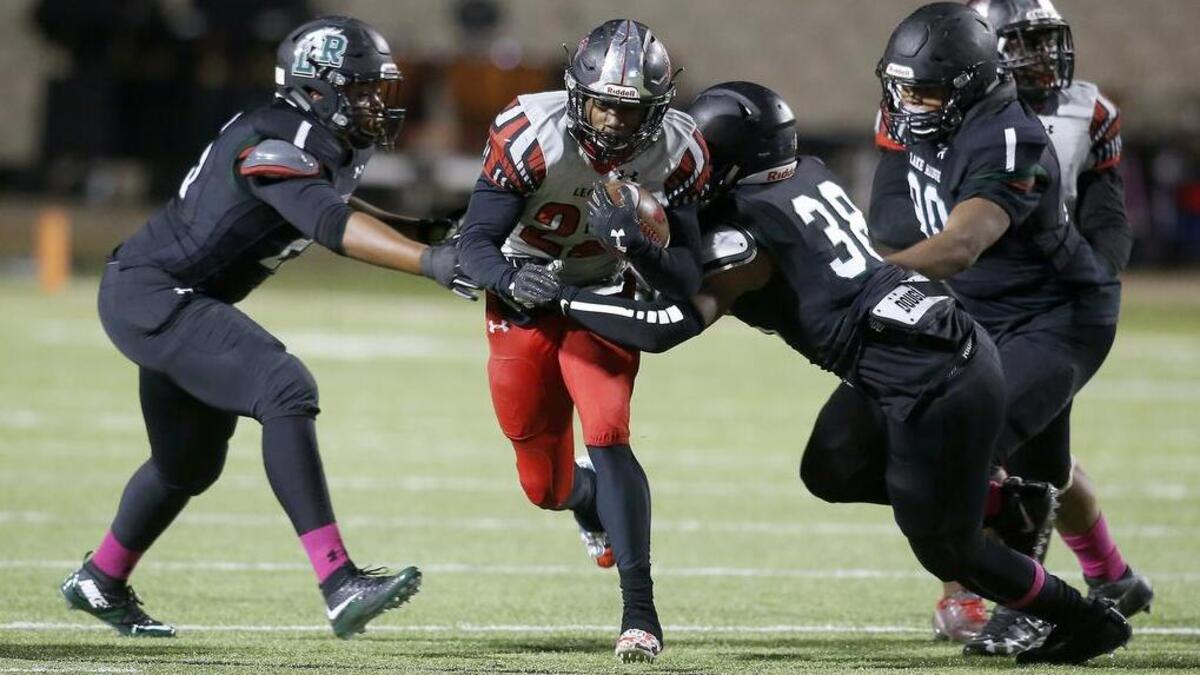 Mansfield Legacy running back Grant Johnson (22) attempts to evade Lake Ridge linebacker Jaden Simmons (38) and defensive end Brandon Nettles (25), Oct. 27, 2017.