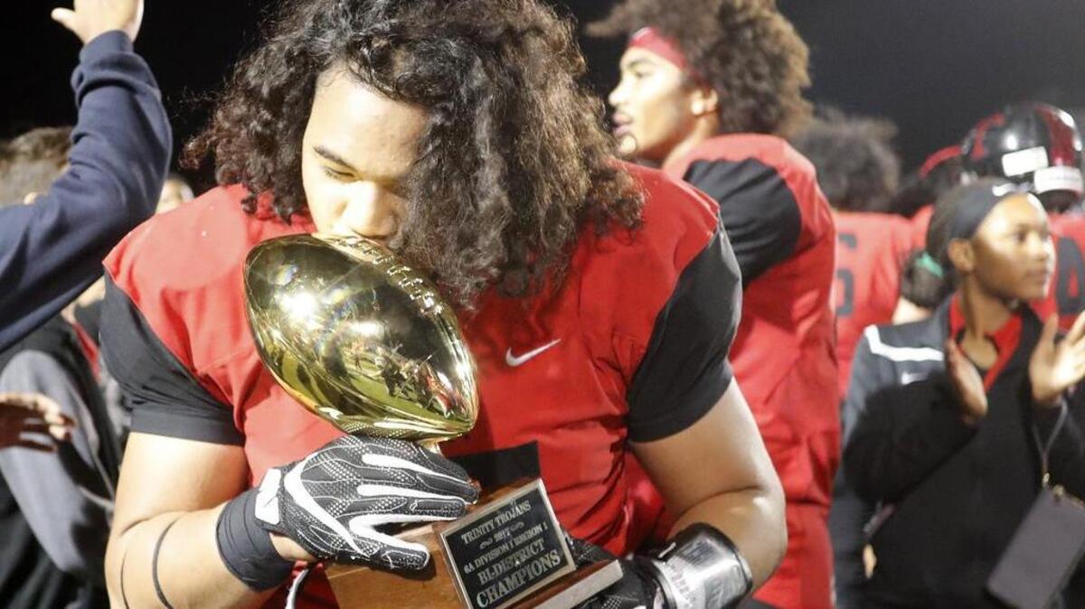 Euless Trinity defensive lineman Will Latu (95) gives the 6A Division I Region I playoff trophy a kiss after Euless Trinity defeated Plano on Friday night at Pennington Field.