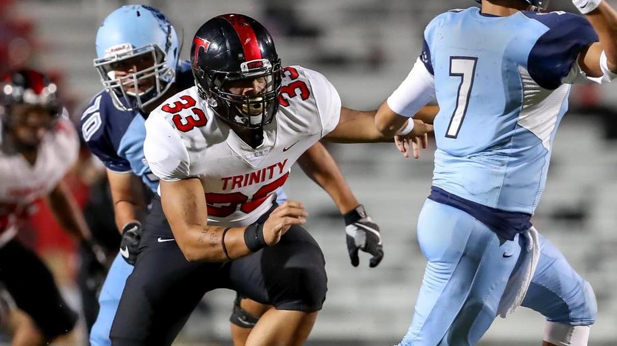 From Week 7, Euless Trinity defensive end Izaih Filikitonga (33) pressures L.D. Bell quarterback Mason Ornelas (7).