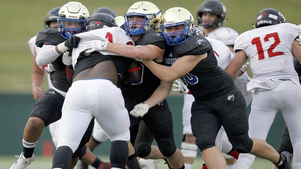 Saginaw Boswell defenders D’shalon Douglas, left, Hunter Harp, center, and Alexander Bennett stop Lubbock Cooper running back Elijah Boyd during their 20-10 playoff win at Memorial Stadium in Wichita Falls on, Nov. 26, 2016.