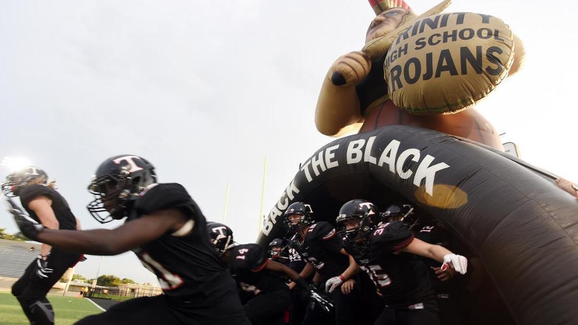 The Euless Trinity Trojan football team runs out of the inflatable tunnel before thier game against Broken Arrow, Okla., Friday, August 26, 2016 at Pennington Field in Bedford.