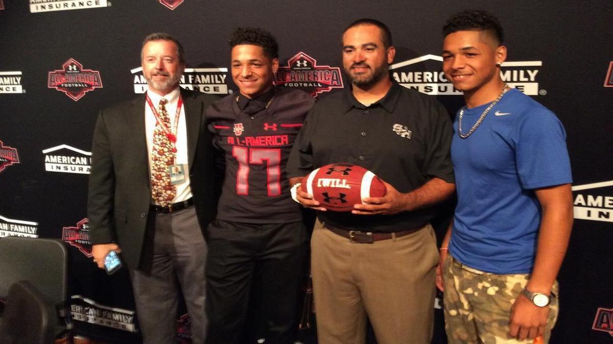 Fort Worth South Hills senior receiver Tylan Wallace, second from left, is presented with his Under Armour/ESPN All-American jersey Monday at the high school. Also pictured are Fort Worth ISD executive director of athletics Kevin Greene, left, South Hills football coach J.J. Resendez (with football) and Tylan’s brother, Tracin Wallace.