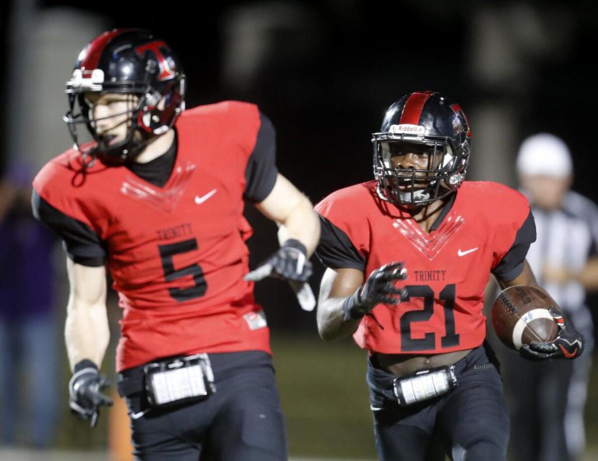 Trinity running back Courage Keihn (21) follows his lead blocker, Toby Harrah (5), during Friday’s game.