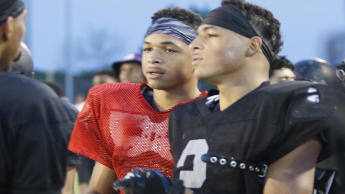 South Hills quarterback Tracin Wallace and twin brother wide receiver Tylan visit with teammates on the sidelines during a football scrimmage between South Hills and Dunbar Friday Aug. 19, 2016.
