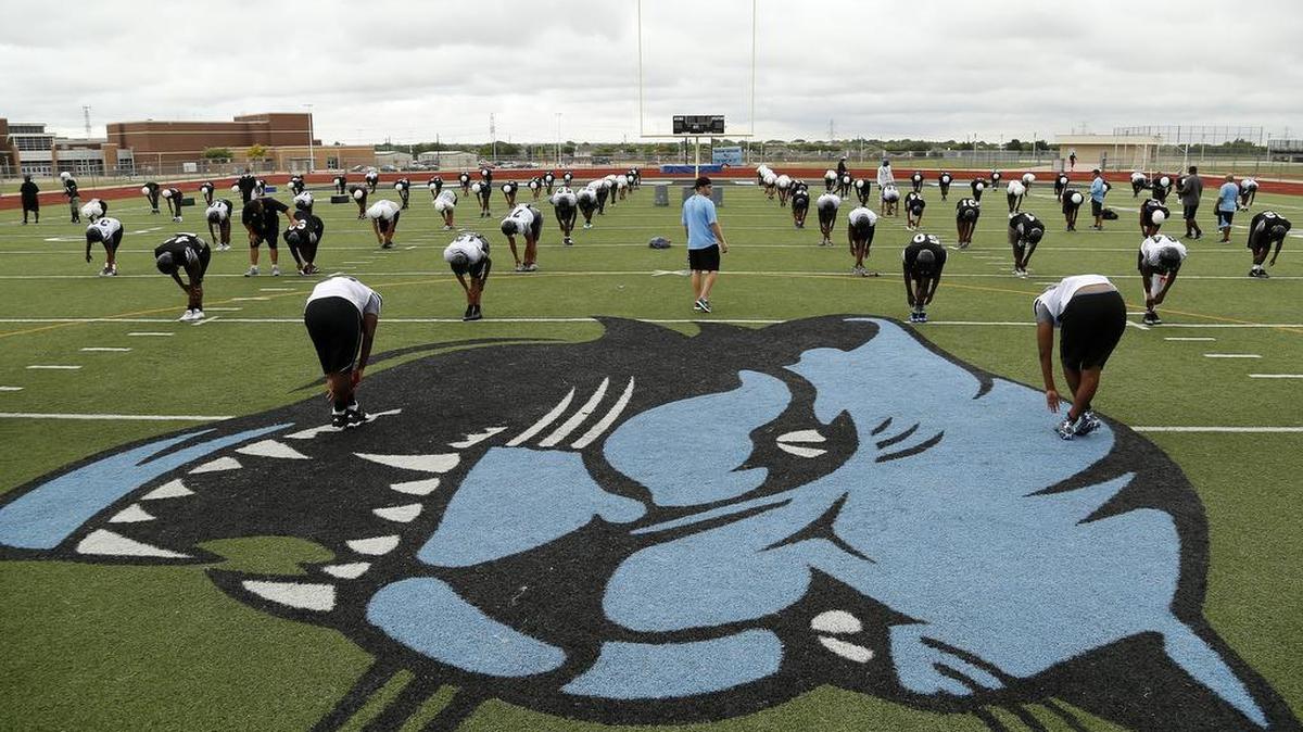 Arlington Seguin football players stretch before August conditioning work.