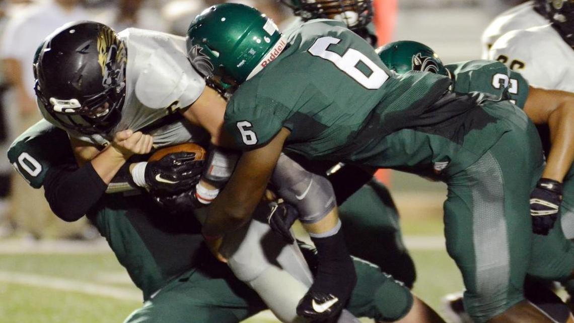 In a 2015 game, Kennedale’s Dustin Masner, left, and Baron Browning, right, wrap up Kaufman’s Devyn Morris for a loss