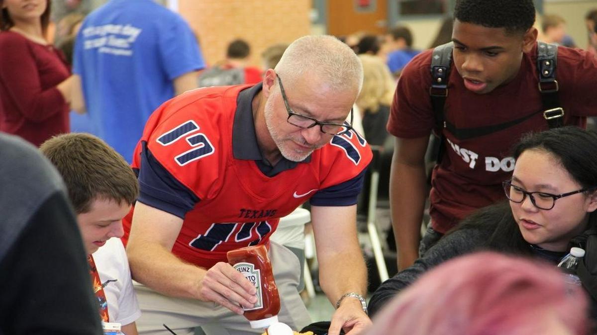 Dr. Ron Myers, the principal at Byron Nelson, brought his own ketchup bottle to serve students at Northwest after his school lost to the Texans.