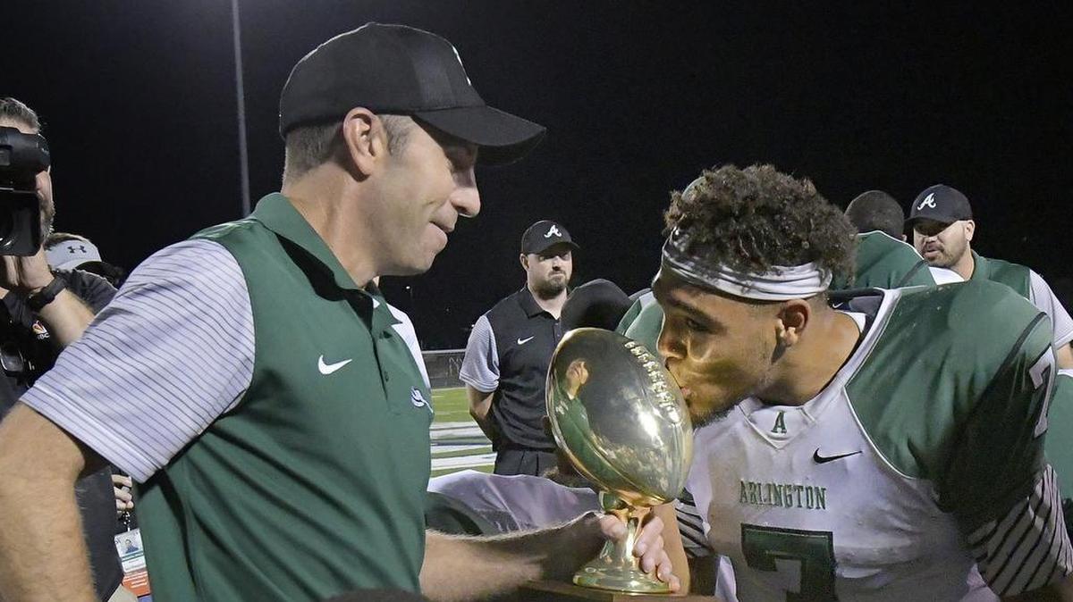 Arlington Colts head coach Scott Peach holds the trophy while Arlington Colts D'montae Davis (7) kisses it after they beat Fossil Ridge in the playoffs in November. Davis is up for an honor at the 1st Down Club awards.