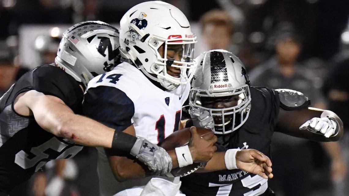 Allen quarterback Grant Tisdale is caught for a loss by Martin’s Spencer Trussell, left, and Emmanuel Sadala.