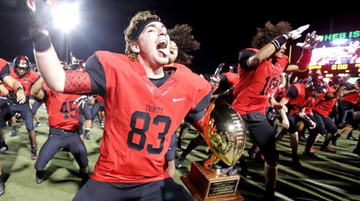 Trinity tight end Lane Polston (83) celebrates with the trophy and teammates after winning the 6A Division I Region I playoff game at Pennington Field Friday November 17, 2017. Trinity defeated Plano with the first play of overtime 28-21.