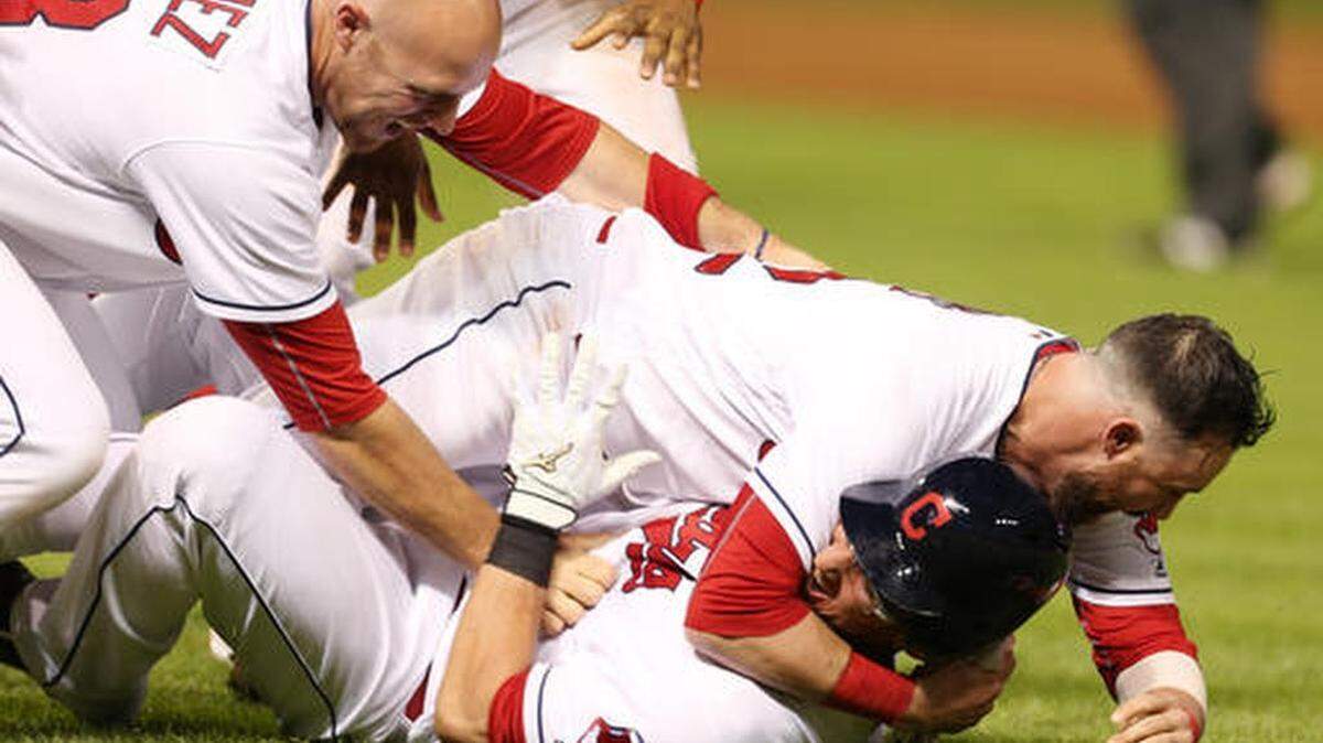 Cleveland Indians' Yan Gomes, bottom, is tackled by Jason Kipnis and Chris Gimenez, left, after hitting a single to score the winning run against the Texas Rangers during the 11thinning of a baseball game Wednesday, June 1, 2016, in Cleveland. The Indians won 5-4.