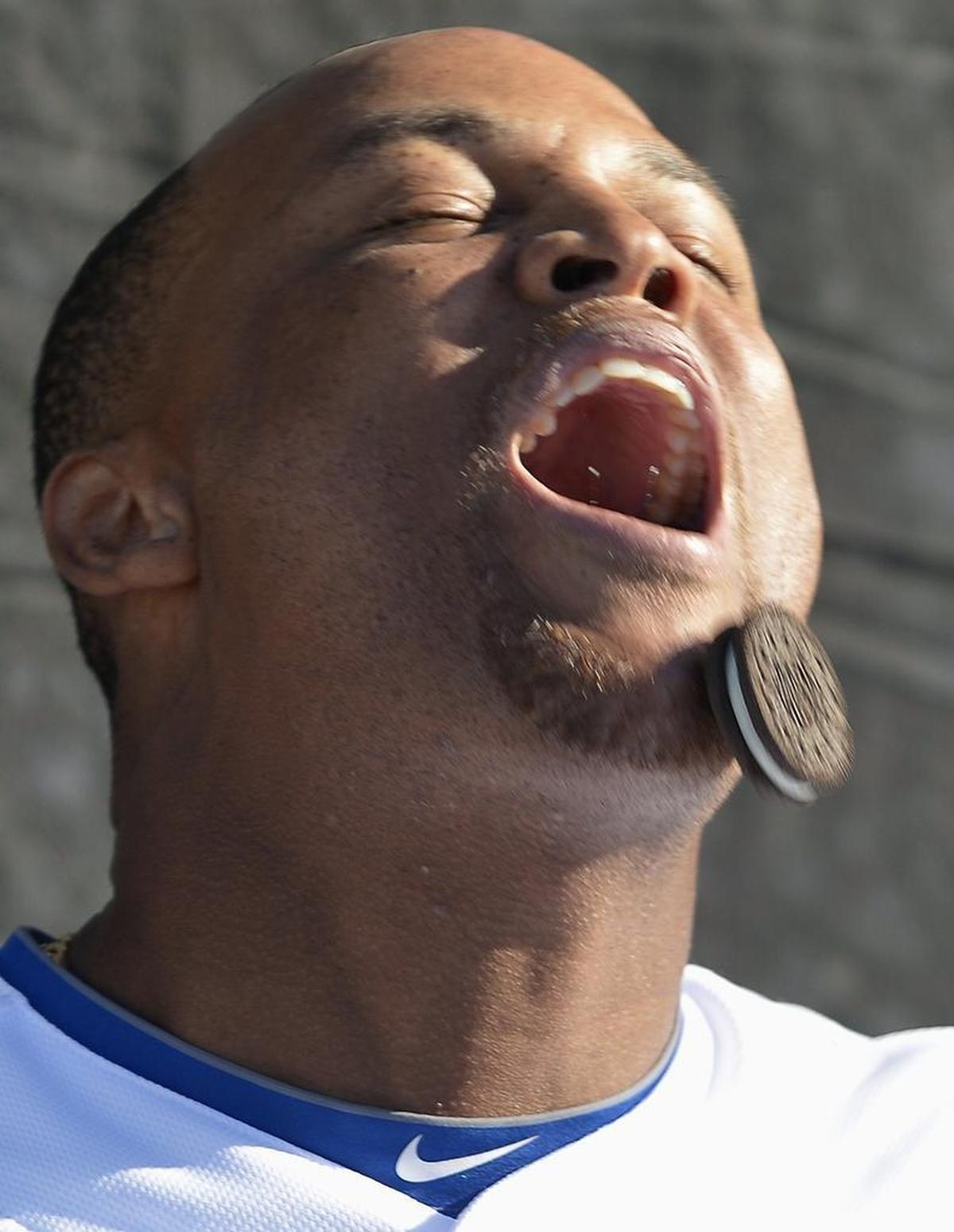 Rangers third baseman Adrian Beltre tries to, unsuccessfully, guide a cookie down his face and into his mouth without the use of this hands during the taping of a bit for the Texas Rangers ballpark video screens during spring training.