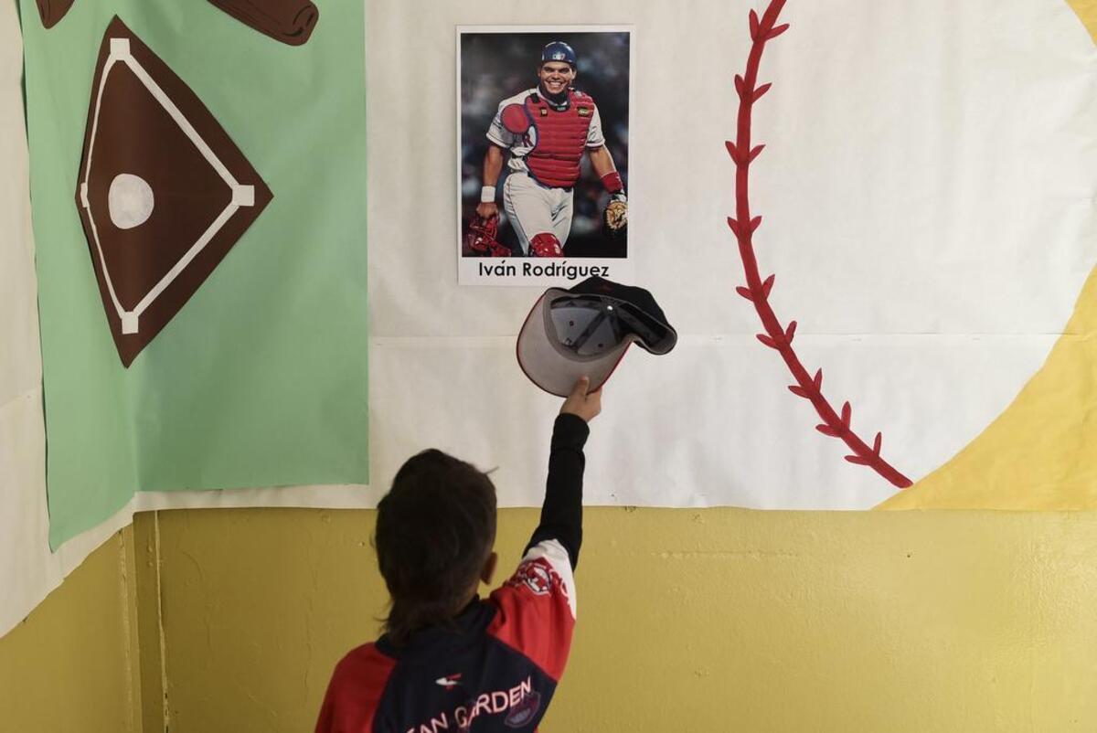A student raises his cap to an image of Pudge Rodriguez, who was celebrating at his hometown school, José Gualberto Padilla Elementary, in Vega Baja, Puerto Rico, Friday, Jan. 27. Rodriguez is the fourth native Puerto Rican inducted into the Baseball Hall of Fame and is the youngest inductee at 45.