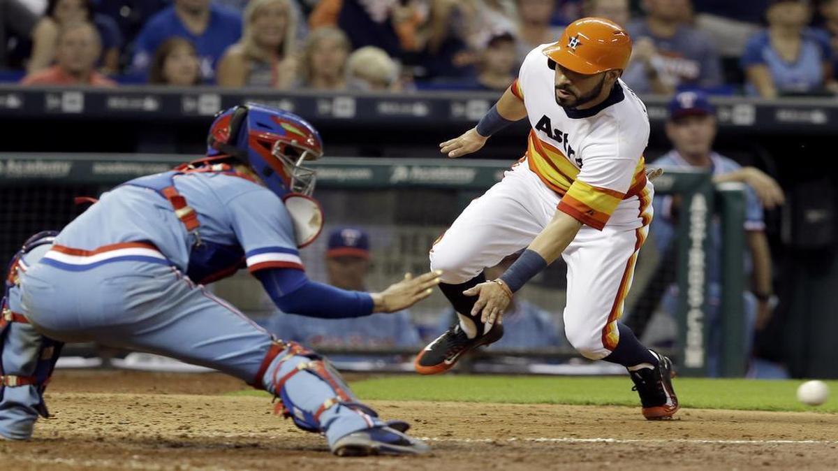 
Astros’ Marwin Gonzalez, right, races the ball to home plate and Rangers catcher Robinson Chirinos to score in the eighth inning Saturday. Texas held on to beat Houston 7-6.
