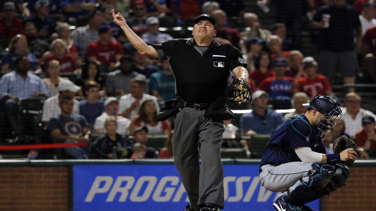 Home plate umpire Jeff Nelson tosses Rangers manager Jeff Banister from the game in the fourth inning Tuesday night as Mariners catcher Mike Zunino kneels at the plate.