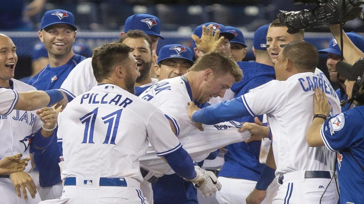 The Blue Jays’ Justin Smoak is mobbed by teammates after his two-run homer in the bottom of the 10th on Tuesday night.