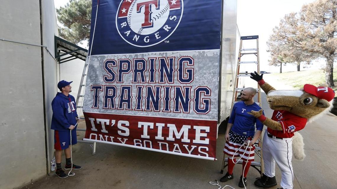 Rangers pitcher Chi Chi Gonzalez, left, catcher Jonathan Lucroy, center, and team mascot Rangers Captain help send off a truck filled with equipment heaed to the club’s spring training facility in Surprise, Ariz.