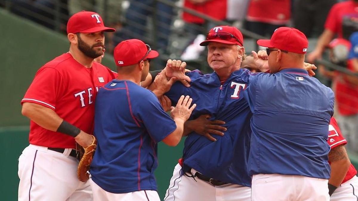 Rangers bench coach Steve Buechele gets pulled off the field by players and coaches after a bench-clearing fight broke out in the 8th inning Sunday of Texas’ 7-6 win over Toronto.