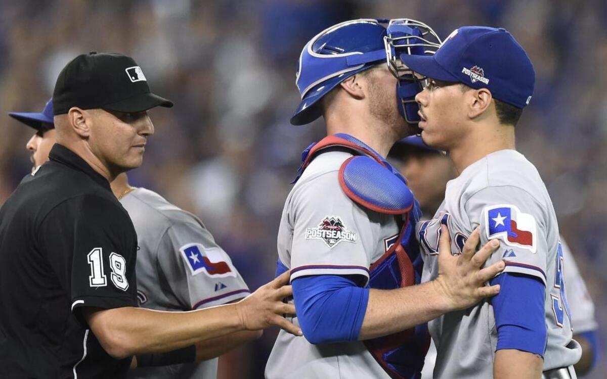 
Rangers’ reliever Keone Kela, right, is held back by catcher Chris Gimenez, center, in the 13th inning Friday after exchanging words with Blue Jays’ hitter Josh Donaldson. Kela struck him out and Texas beat Toronto 6-4 take a 2-0 lead in the ALDS.
