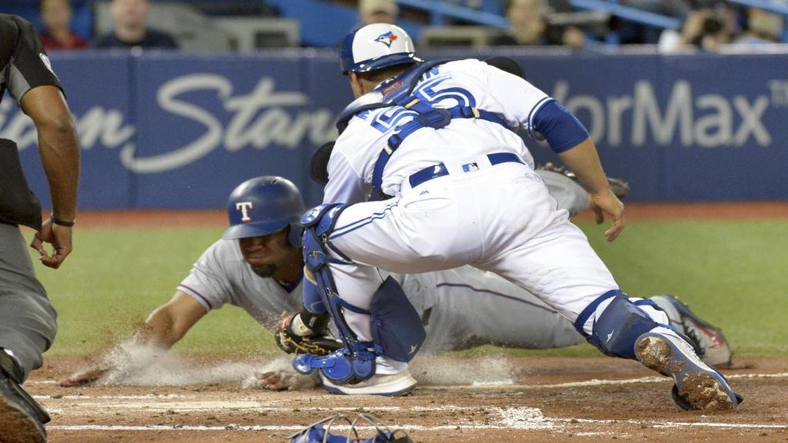 Russell Martin, right, tags out Elvis Andrus at home plate in the third inning Friday night at Rogers Centre in Toronto. The Blue Jays beat the Rangers 7-6.