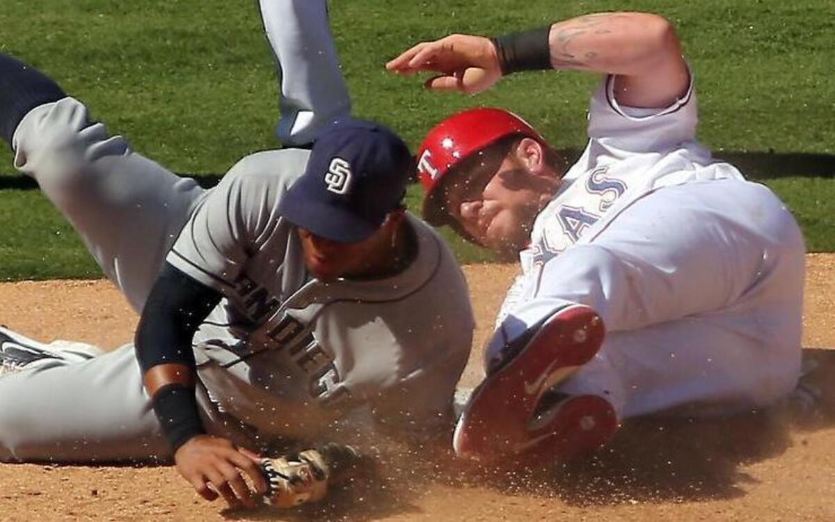 
San Diego Padres third baseman Yangervis Solarte tumbles into Texas Rangers' Josh Hamilton after trying to make the tag at third base in the 8th inning at Globe Life Park in Arlington Sunday, July 12, 2015 
