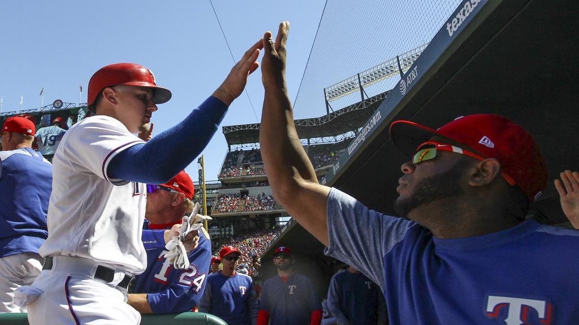 Ryan Rua, left, gets a high five in the dugout after scoring in Sunday’s game at Globe Life Park.