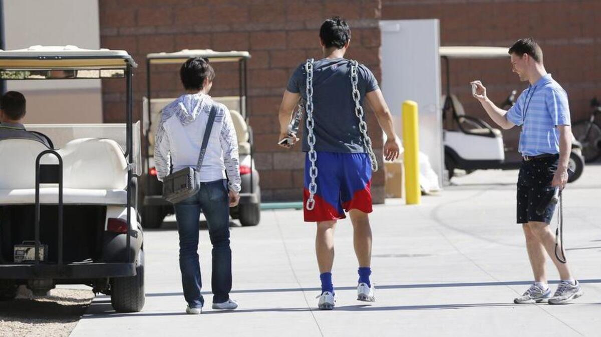 Rangers pitcher Yu Darvish carries two heavy chains to add to his workout during Monday’s spring training session in Surprise, Ariz.