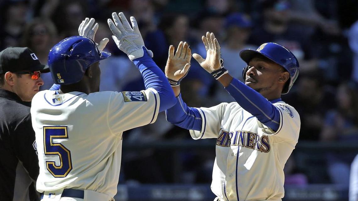 Guillermo Heredia (5) and Jarrod Dyson share congratulations after they scored on a single by Danny Valencia against the Texas Rangers in the seventh inning of a baseball game Sunday, May 7, 2017, in Seattle. (AP Photo/Elaine Thompson)