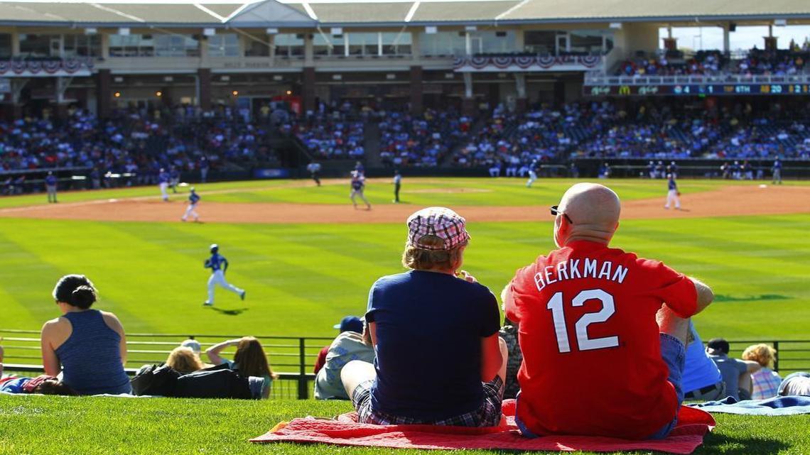 Rangers fans enjoy a spring-training game from the grassy berm in the outfield at Surprise Stadium.