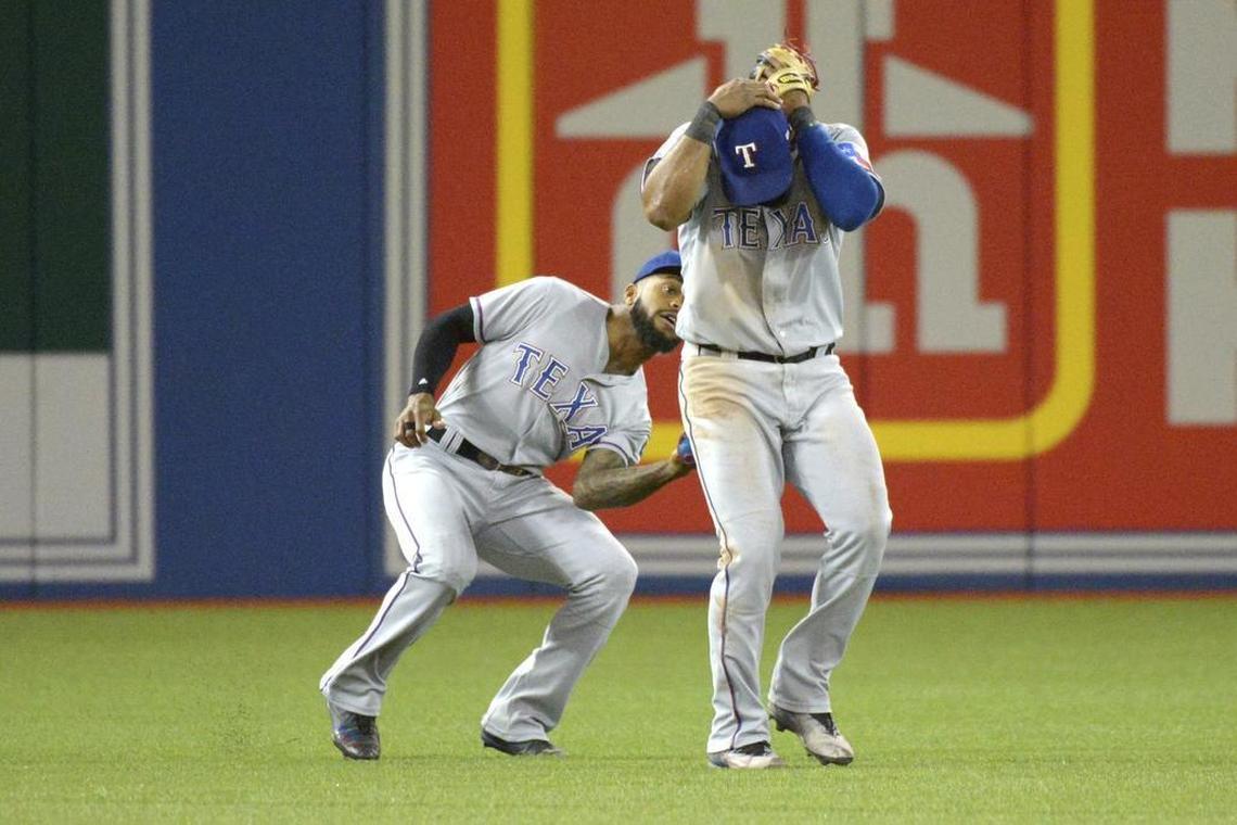 Left fielder Delino DeShields, left, makes a catch while shortstop Elivs Andrus covers his head in the third inning Friday night at Rogers Centre. Rangers fielders nearly ran into each other in each of the three games in Toronto.