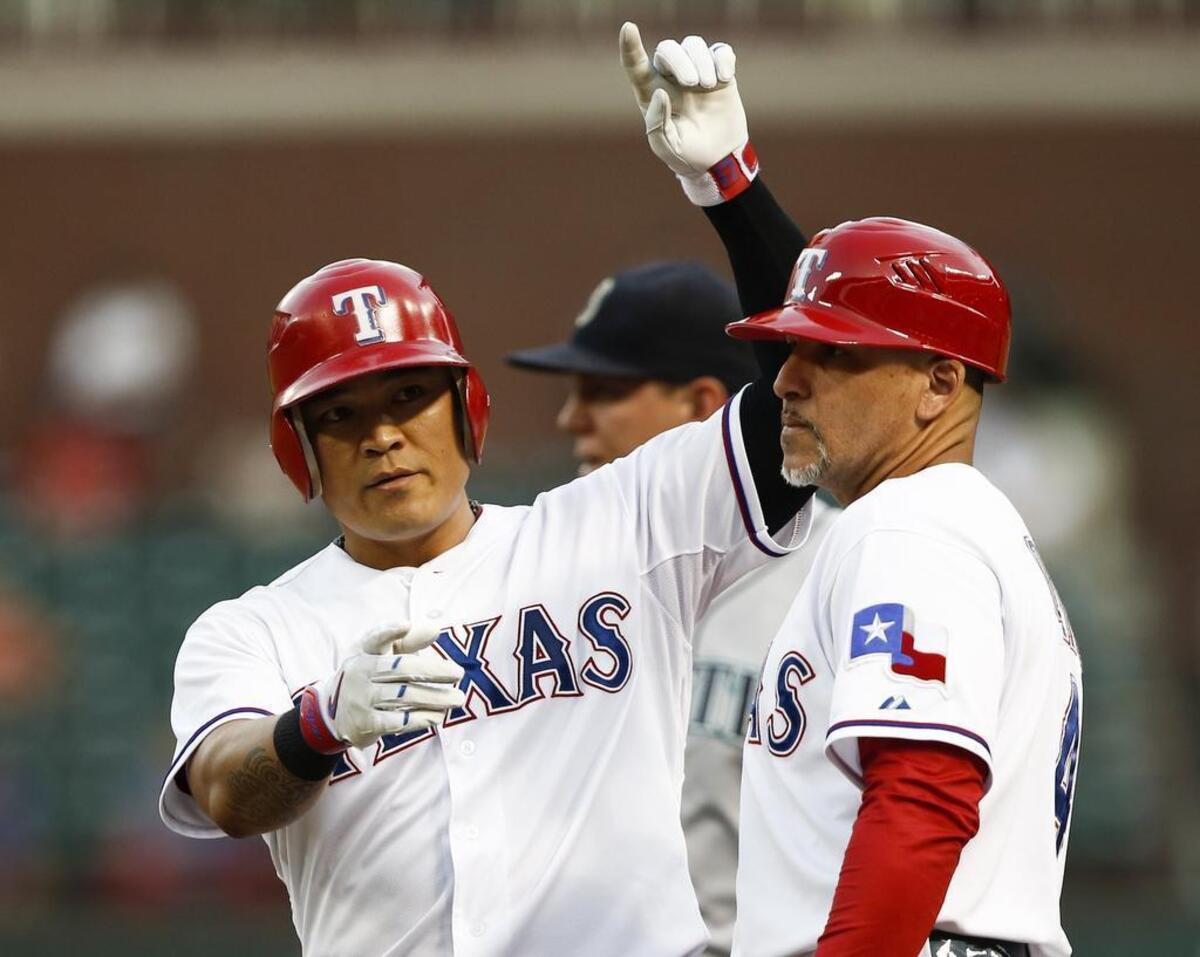 Here’s the two-flapped helmet Shin-Soo Choo usually wears, along with first base coach Hector Ortiz. Choo cracked his red one when he slammed it to the turf after flying out late in Tuesday’s game. Without a replacement, he wore a one-flapped model the next two games and collected seven hits. 
