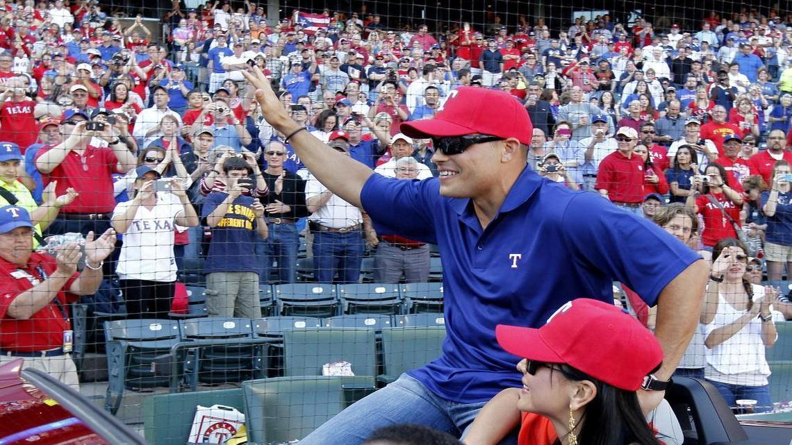 Pudge Rodriguez rides in a car with his wife Claudia Gomez and waves to fans after a pregame ceremony at Globe Life Park in April 2012.