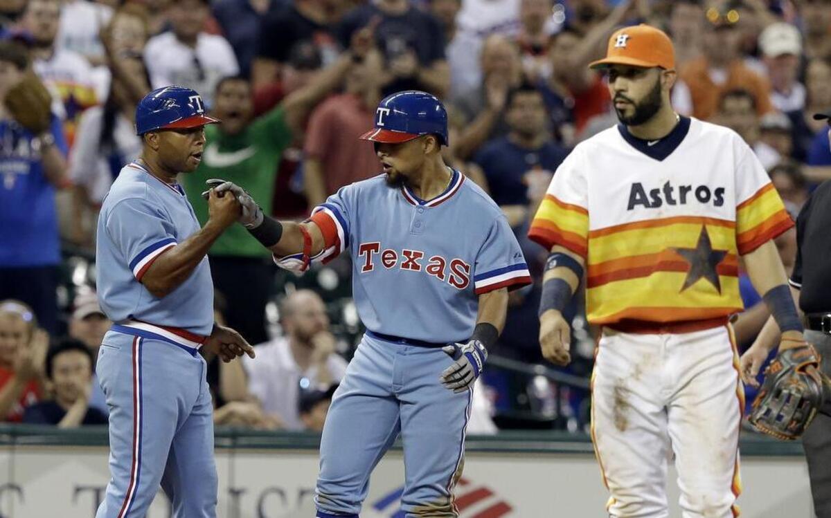 
Rangers third base coach Tony Beasley, left, congratulates Rougned Odor on a triple as Houston Astros third baseman Marwin Gonzalez walks away during a game in July.
