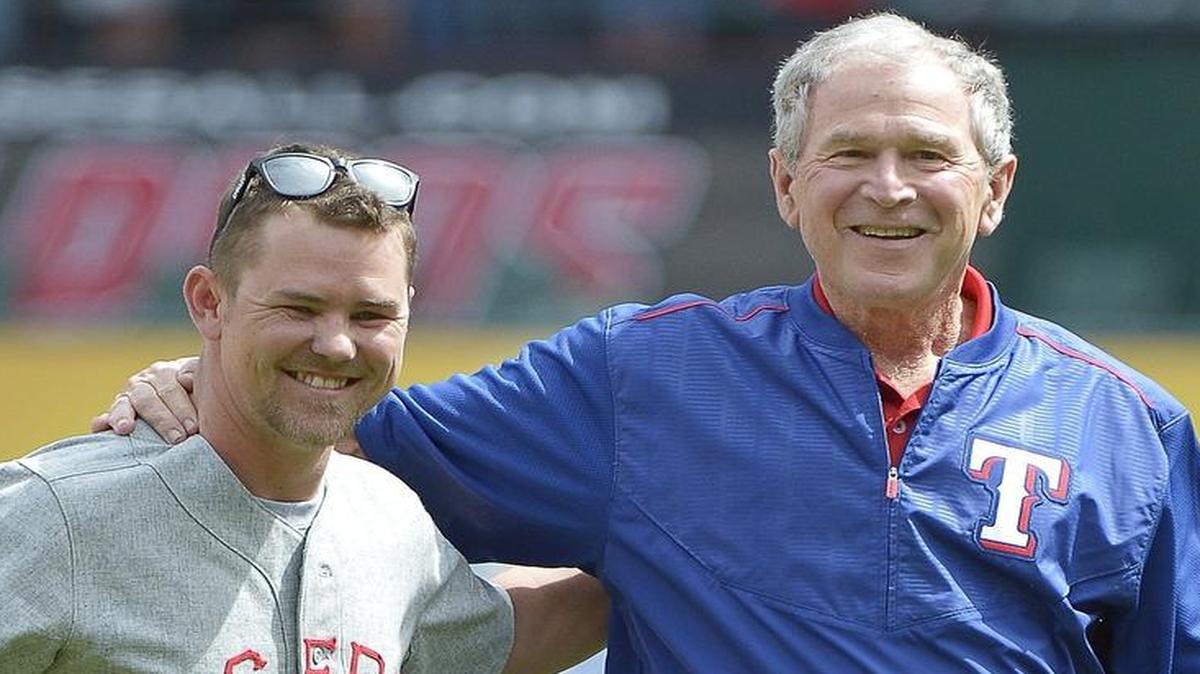 Retired United States Air Force Staff Sergeant Nicholas Bradley gets a hug from President George W. Bush after throwing out the ceremonial first pitch before the Rangers home opener in 2015.
